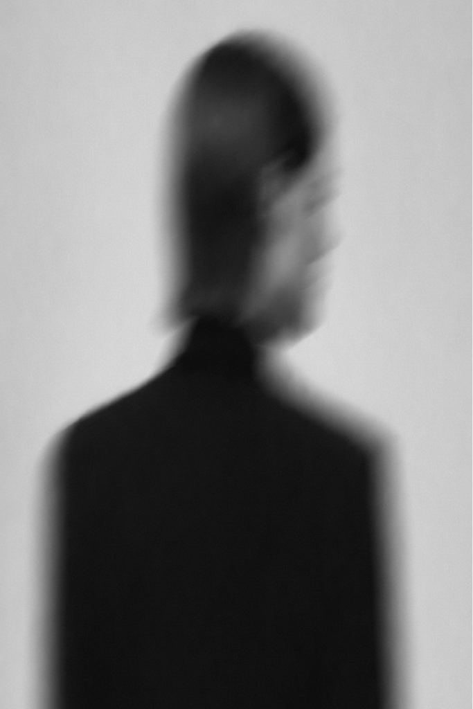 A close-up portrait partly obscured by soft folded fabric