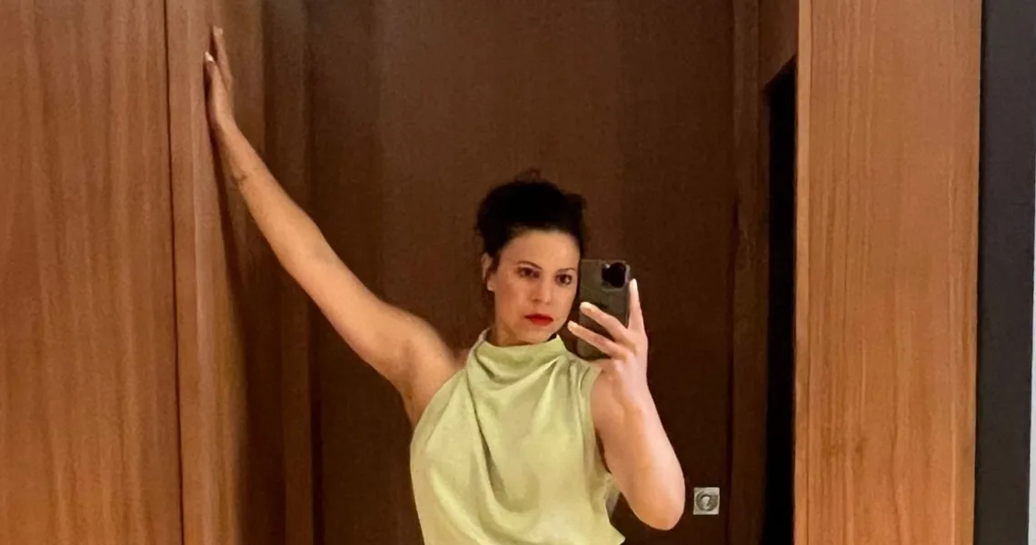 Arelis Caban-Oberst, founder of Archeva, in a doorway with one arm raised.